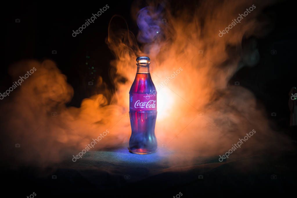 Baku, Azerbaijan 13th January 2018, Coca-Cola Classic in a glass bottle on dark toned foggy Background. Coca Cola, Coke is the most popular carbonated soft drink beverages sold around the world