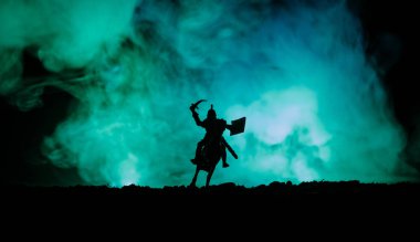 Süvari ve piyade ile ortaçağ savaş sahnesi. Siluetleri şekiller ayrı nesneler olarak mücadele koyu tonda sisli arka plan savaşçılar arasında. Gece çekimi.