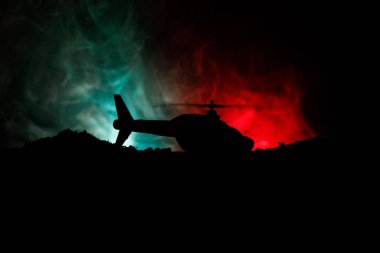Askeri helikopter çatışma bölgesinden uçmaya hazır silüeti. Gece görüntüleri çöl sisli tonda sırt ile başlayarak helikopter ile dekore edilmiştir. Seçici odak.