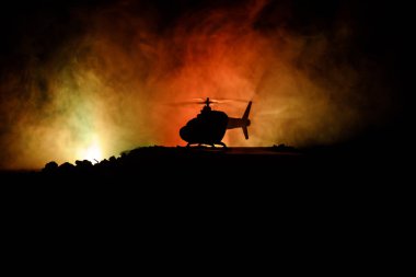 Askeri helikopter çatışma bölgesinden uçmaya hazır silüeti. Gece görüntüleri çöl sisli tonda sırt ile başlayarak helikopter ile dekore edilmiştir. Seçici odak.