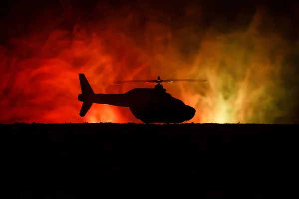 Silhouette of military helicopter ready to fly from conflict zone. Decorated night footage with helicopter starting in desert with foggy toned backlit. Selective focus. — Stock Photo, Image