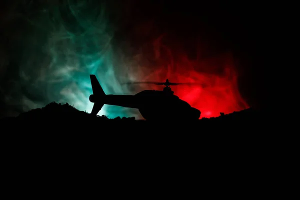 Silueta de helicóptero militar lista para volar desde zona de conflicto. Imágenes nocturnas decoradas con helicóptero comenzando en el desierto con niebla tonificada retroiluminada. Enfoque selectivo . —  Fotos de Stock