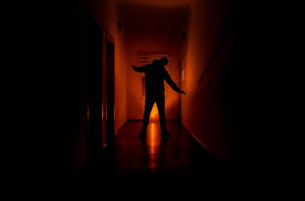 Темний коридор з кабінетними дверима і вогнями з силуетом жахливого чоловіка, що стоїть з різними пози . — стокове фото