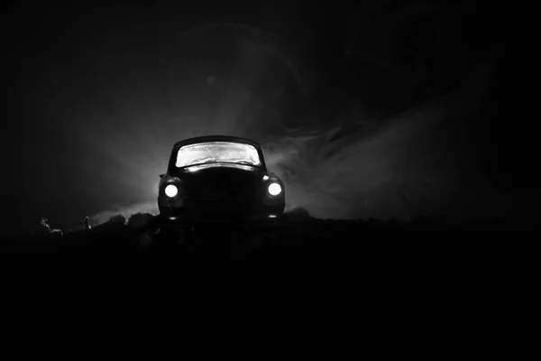 Silhouette della vecchia auto d'epoca in fondo scuro nebbioso tonica con luci incandescenti in scarsa luce, o silhouette della vecchia macchina crimine sfondo scuro . — Foto Stock
