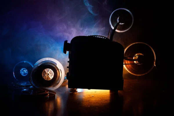 Projector de cinema de estilo antigo, close-up. Projetor de filme em um fundo de madeira com iluminação dramática e foco seletivo. Filmes e conceito de entretenimento — Fotografia de Stock