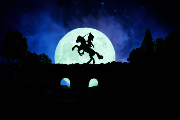 Middeleeuwse slag scène op de brug met de cavalerie en infanterie. Silhouetten van figuren als afzonderlijke objecten, strijd tussen krijgers op donker getinte mistige achtergrond. Nachtbeeld. — Stockfoto