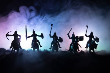 Süvari ve piyade ile ortaçağ savaş sahnesi. Siluetleri şekiller ayrı nesneler olarak mücadele koyu tonda sisli arka plan savaşçılar arasında. Gece çekimi.