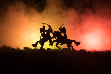 Medieval battle scene with cavalry and infantry. Silhouettes of figures as separate objects, fight between warriors on dark toned foggy background. Night scene. clipart