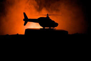 Askeri helikopter çatışma bölgesinden uçmaya hazır silüeti. Gece görüntüleri çöl sisli tonda sırt ile başlayarak helikopter ile dekore edilmiştir. Seçici odak.