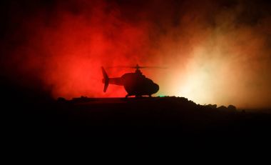 Askeri helikopter çatışma bölgesinden uçmaya hazır silüeti. Gece görüntüleri çöl sisli tonda sırt ile başlayarak helikopter ile dekore edilmiştir. Seçici odak.