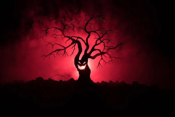 Silueta strašidelný Halloween stromu s hrůzou tváří v mlhavé tmě laděných pozadí se měsíc na zadní straně. Děsivý horor strom s zombie a démon tváře. — Stock fotografie