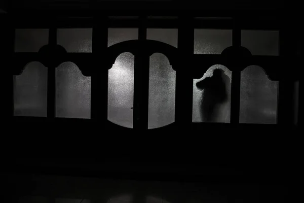 閉じたガラスのドアを通ってドアを不明な影図のシルエット。夜の窓の前で人間のシルエット。ぼやけたシルエットの怖いシーン ハロウィーン コンセプト — ストック写真