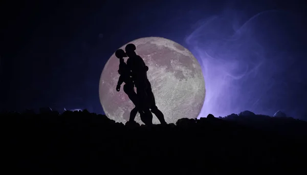 Silueta de pareja besándose bajo luna llena. Chico beso chica mano en luna llena silueta fondo. Concepto de decoración del día de San Valentín. Silueta de pareja amorosa besándose contra la luna — Foto de Stock