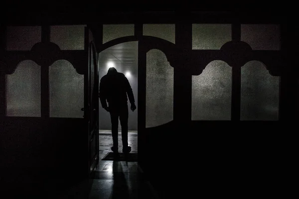 Silhouette of an unknown shadow figure on a door through a closed glass door. The silhouette of a human in front of a window at night. Scary scene halloween concept of blurred silhouette — Stock Photo, Image