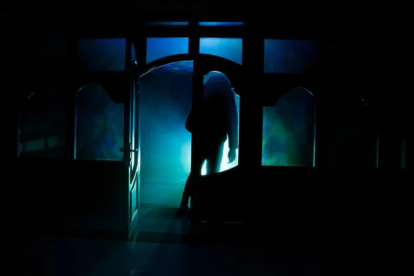 Silhueta de uma figura de sombra desconhecida em uma porta por uma porta de vidro fechada. A silhueta de um humano à frente de uma janela à noite. Cena assustadora halloween conceito de silhueta borrada — Fotografia de Stock