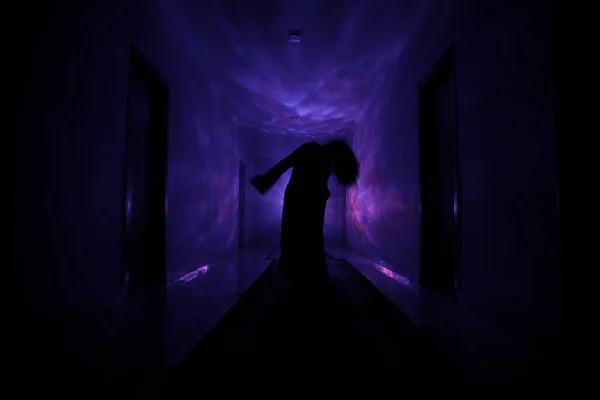 Läskiga siluett i den mörka övergivna byggnaden. Mörk korridor med dörrar skåp och lampor med silhuetten av kusliga skräck person som står med olika poser. — Stockfoto