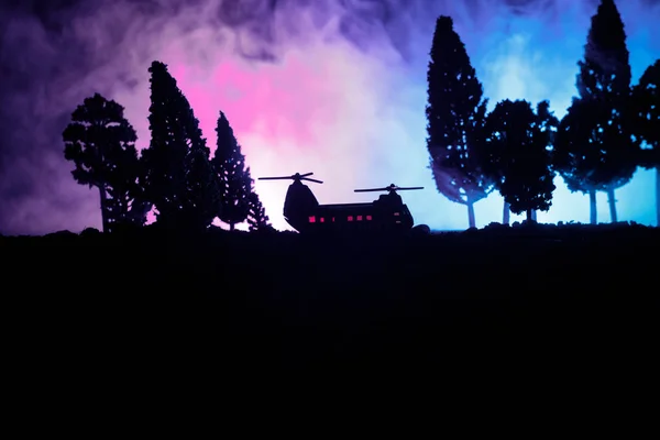 Silhouet van militaire helikopter klaar om te vliegen vanaf conflictgebied. Nacht beelden versierd met helikopter starten in woestijn met mistige afgezwakt achtergrondverlichting. Selectieve aandacht. — Stockfoto