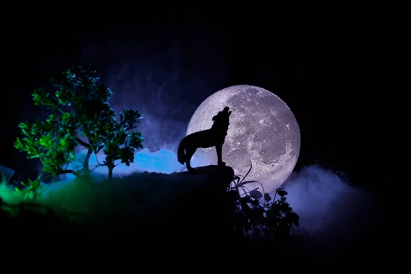 Silhueta de lobo uivante contra fundo enevoado escuro e lua cheia ou lobo em silhueta uivando até a lua cheia. Conceito de horror Halloween . — Fotografia de Stock