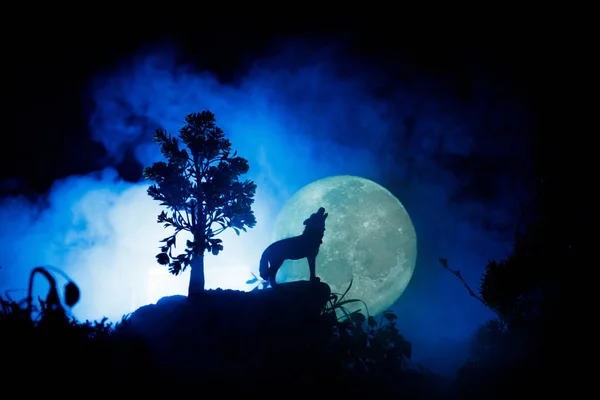 Silhouet van huilende wolf tegen donker getinte mistige achtergrond en volle maan of Wolf in silhouet huilend naar de volle maan. Halloween horror concept. — Stockfoto