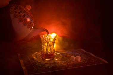 Geleneksel glasse ve ışıklar ve duman siyah zemin üzerine pot Doğu tea. Doğu çay kavramı. Armudu geleneksel Azerbaycan/Türkiye Kupası