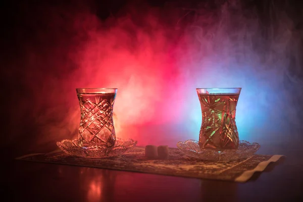 Teh timur dalam kaca tradisional dan pot dengan latar belakang hitam dengan lampu dan asap. Konsep teh Timur. Armudu tradisional Azerbaijan / cangkir Turki — Stok Foto