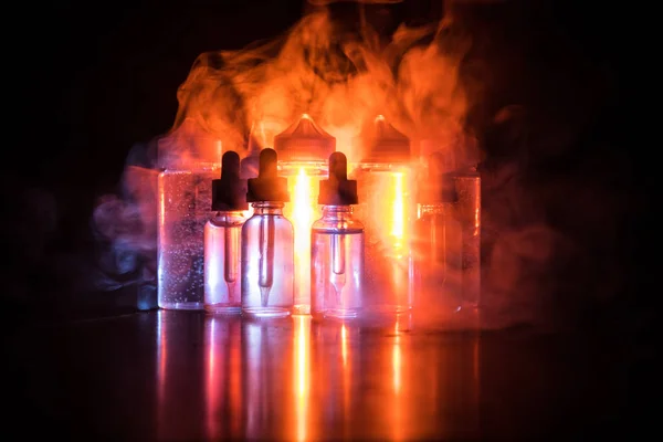 Concepto Vape. Nubes de humo y botellas de vapor líquido sobre fondo oscuro. Efectos luminosos — Foto de Stock