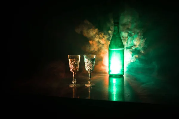 Dos vasos de vodka con botella sobre fondo oscuro niebla estilo club con luces brillantes (Láser, Stobe) Multi color. Club bebidas decoración temática. Espacio vacío — Foto de Stock