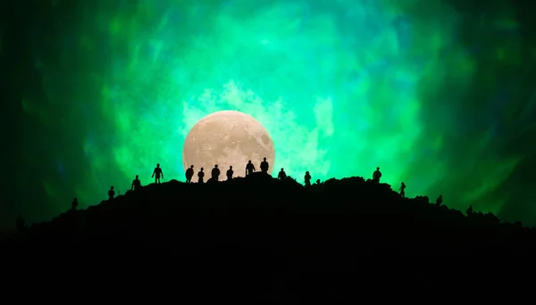 Eng weergave menigte van zombies op heuvel met spooky bewolkte hemel met mist en opkomende volle maan. Silhouet groep van zombie lopen onder de volle maan. — Stockfoto