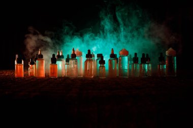 Vape kavramı. Duman bulutları ve vape sıvı şişe koyu arka plan üzerinde. Işık efektleri. Arka plan veya vape reklam veya vape arka plan olarak yararlı.