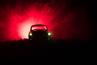 Eski model araba sisli karanlıkta parlayan ışıklar ile arka plan tonda siluet eski ışık yetersiz veya eski siluet suç araba koyu arka plan.