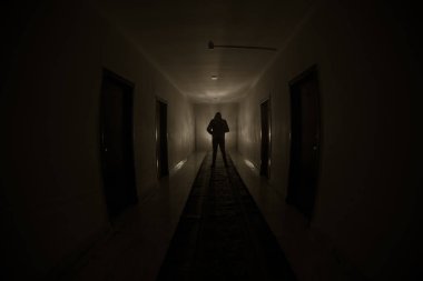 Ürpertici siluet koyu terk edilmiş binada. Kabine kapılar ve ışıkları ile farklı pozlar duran korkunç korku kişi silueti ile karanlık koridor.