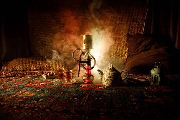 Charbons chauds narguilé sur bol de shisha faisant des nuages de vapeur à l'intérieur arabe. Ornement oriental sur la cérémonie du thé oriental tapis. Chicha orientale élégante dans l'obscurité avec contre-jour . — Photo