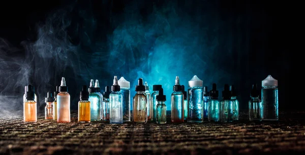 Koncepcja Vape. Pali, chmury i vape płyn butelki na ciemnym tle. Efekty świetlne. Użyteczne jako lub vape ogłoszenie lub tle vape. — Zdjęcie stockowe