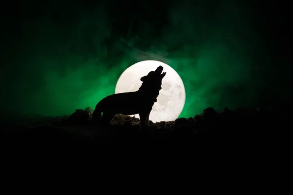 Sylwetka wycie wilka przeciwko ciemnym stonowanych mglisty tło i pełni księżyca lub wilk w sylwetka wycie do księżyca w pełni. Halloween horror koncepcja. — Zdjęcie stockowe