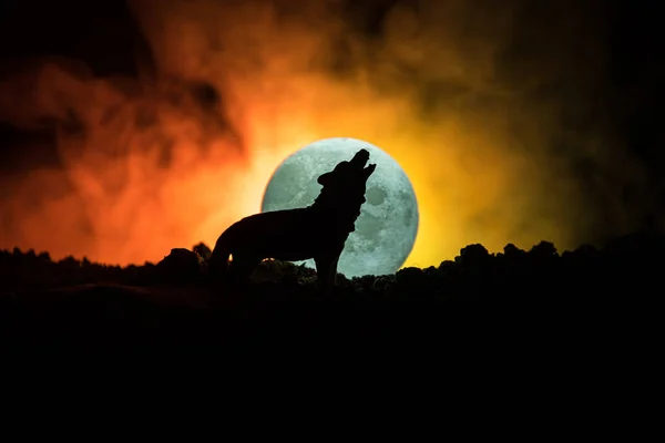 Silueta de lobo aullando contra fondo de niebla tonificado oscuro y luna llena o lobo en silueta aullando a la luna llena. Halloween concepto de horror . — Foto de Stock