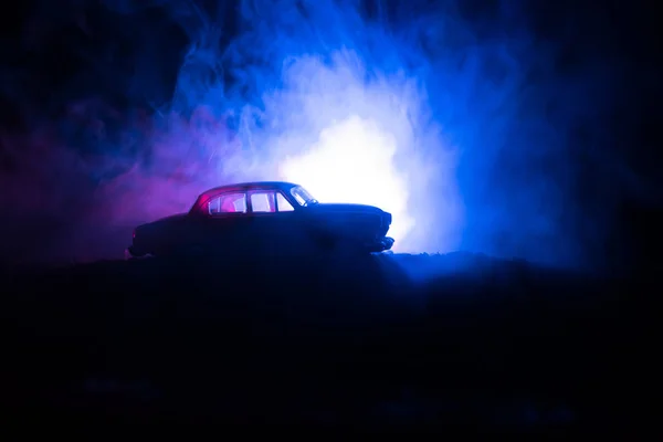 Silueta de coche viejo de la vendimia en fondo oscuro nebuloso tonificado con luces brillantes en la luz baja, o silueta de coche viejo crimen fondo oscuro . —  Fotos de Stock