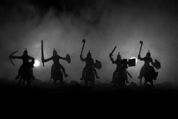 Scène de bataille médiévale avec cavalerie et infanterie. Silhouettes de figures comme objets séparés, lutte entre guerriers sur fond brumeux foncé. Scène nocturne . — Photo