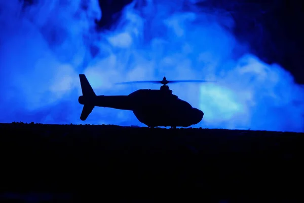 Silhouette of military helicopter ready to fly from conflict zone. Decorated night footage with helicopter starting in desert with foggy toned backlit. Selective focus. — Stock Photo, Image