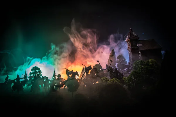 Scène de bataille médiévale avec cavalerie et infanterie. Silhouettes de figures comme objets séparés, lutte entre guerriers sur fond brumeux foncé. Scène nocturne . — Photo