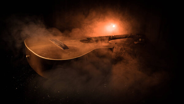 Music concept. Acoustic guitar on a dark background under beam of light with smoke. Guitar with Strings, close up. Selective focus. Fire effects. Surreal guitar
