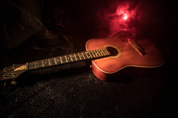 Concept musical. Guitare acoustique sur fond sombre sous faisceau de lumière avec fumée. Guitare à cordes, gros plan. Concentration sélective. Effets de feu. Guitare surréaliste — Photo