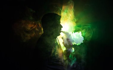 Bir mod tutarak Vaping adam. Buhar bulutu. karanlık sisli bulutlar duman arka plan tonda. Vaping elektronik sigara duman bir sürü ile. Vape kavramı. Seçici odak
