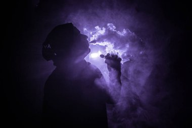 Bir mod tutarak Vaping adam. Buhar bulutu. karanlık sisli bulutlar duman arka plan tonda. Vaping elektronik sigara duman bir sürü ile. Vape kavramı. Seçici odak