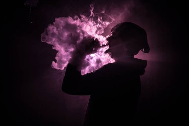 Bir mod tutarak Vaping adam. Buhar bulutu. karanlık sisli bulutlar duman arka plan tonda. Vaping elektronik sigara duman bir sürü ile. Vape kavramı. Seçici odak