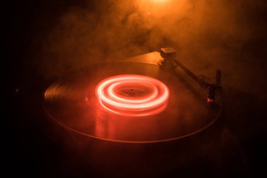 Pikap vinil plak çalar. Retro ses ekipmanları için disk jokey. Dj mix ve müzik çalmak için ses teknolojisi. Yangın arka plan duman ile yanan karşı oynanan vinil kaydı