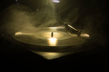 Pikap vinil plak çalar. Retro ses ekipmanları için disk jokey. Dj mix ve müzik çalmak için ses teknolojisi. Yangın arka plan duman ile yanan karşı oynanan vinil kaydı
