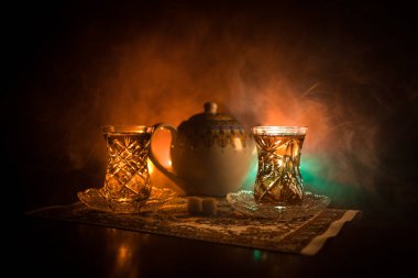 Geleneksel glasse ve ışıklar ve duman siyah zemin üzerine pot Doğu tea. Doğu çay kavramı. Armudu geleneksel Azerbaycan/Türkiye Kupası. Seçici odak. Bardak çay