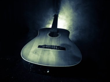 Müzik konsepti. Akustik gitar duman ile ışık altında karanlık bir arka plan üzerinde. Gitar dizeleri ile kapatın. Seçici odak. Yangın etkileri.
