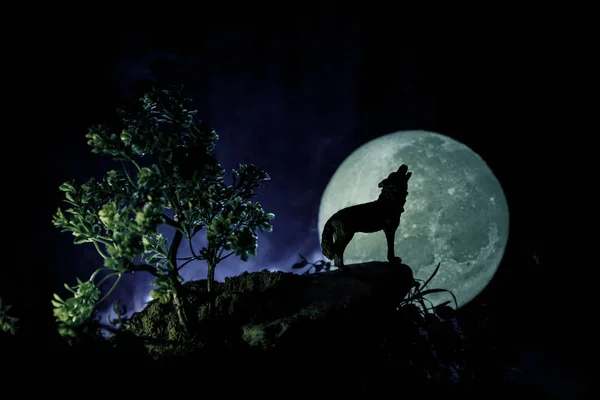 Silueta de lobo aullando contra fondo de niebla tonificado oscuro y luna llena o lobo en silueta aullando a la luna llena. Halloween concepto de horror . —  Fotos de Stock