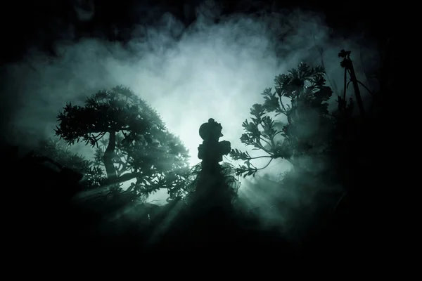 Horror Halloween decorated conceptual image. Alone girl with the light in the forest at night. Silhouette of girl standing between trees with surreal light . Selective focus. — Stock Photo, Image